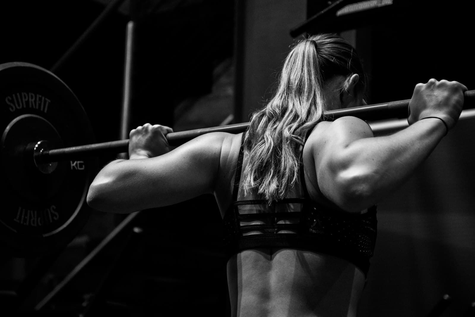 Frau führt eine Kniebeuge mit Langhantel im Fitnesscenter aus