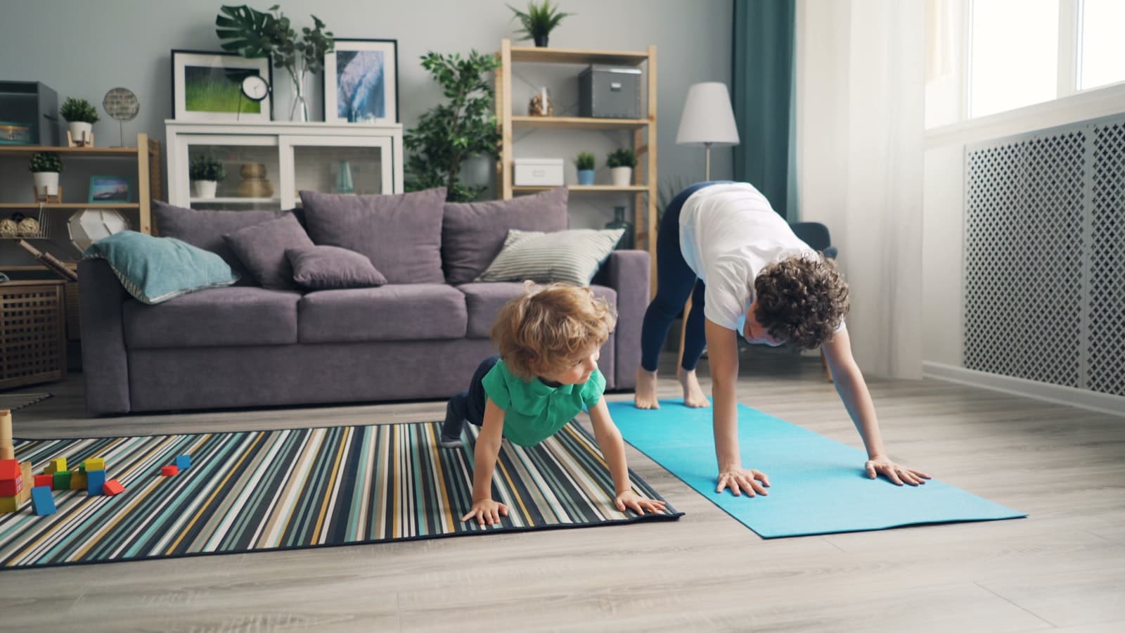 Mutter trainiert zuhause auf der Yogamatte neben ihrem Kind